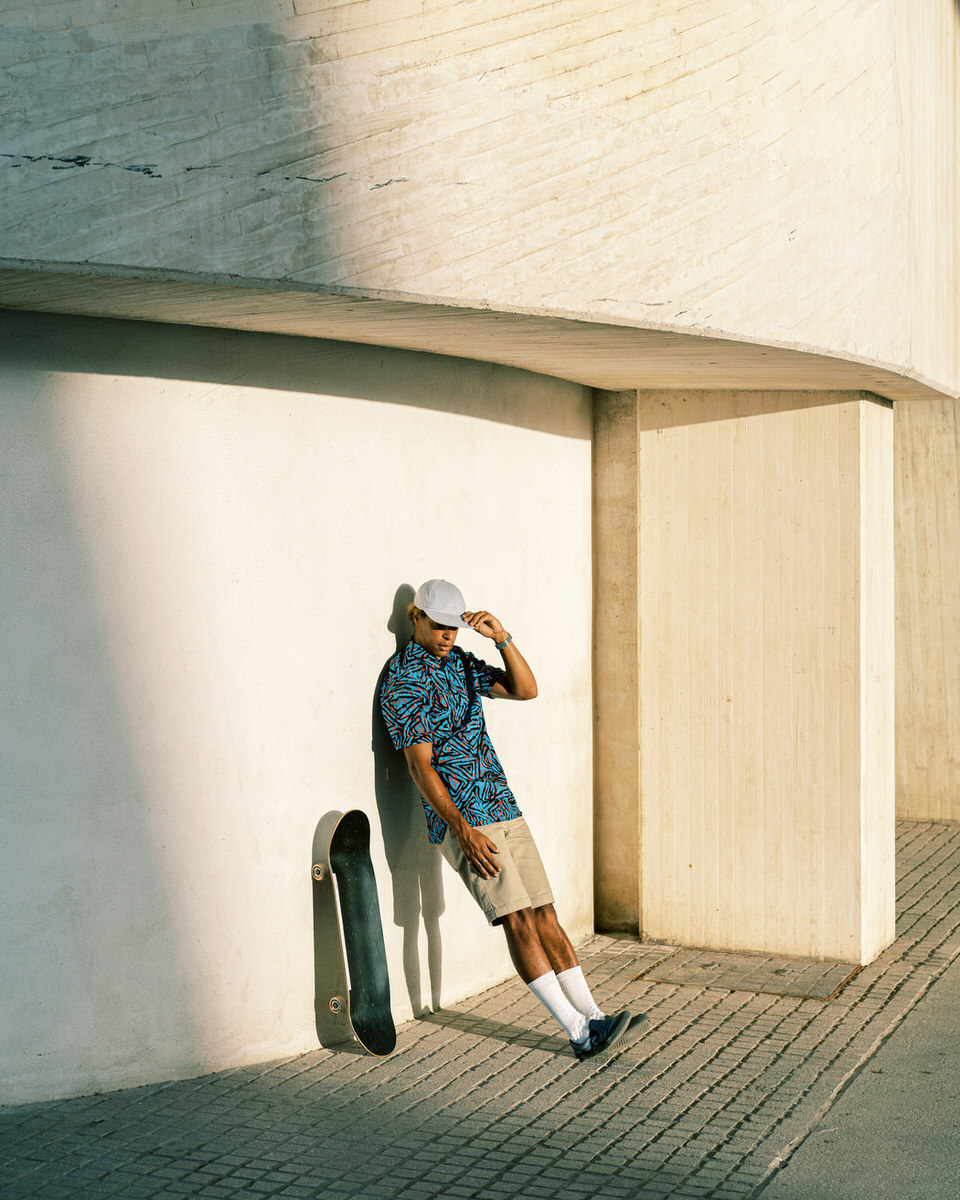 Ethnic man with skateboard outside modern building