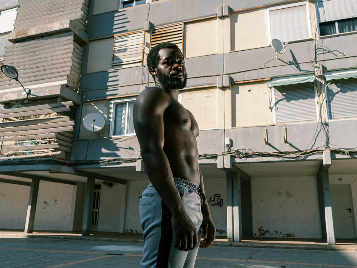 Muscular black sportsman standing on sports ground