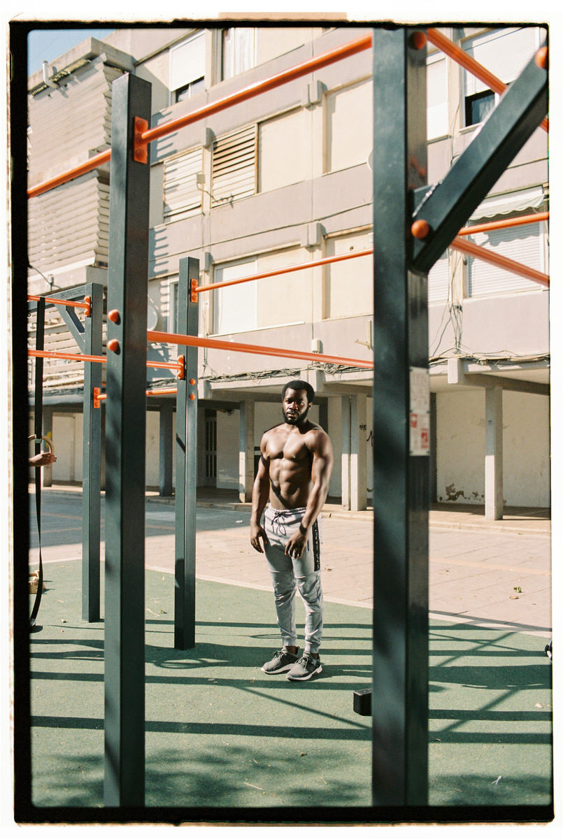 Muscular black sportsman standing on sports ground