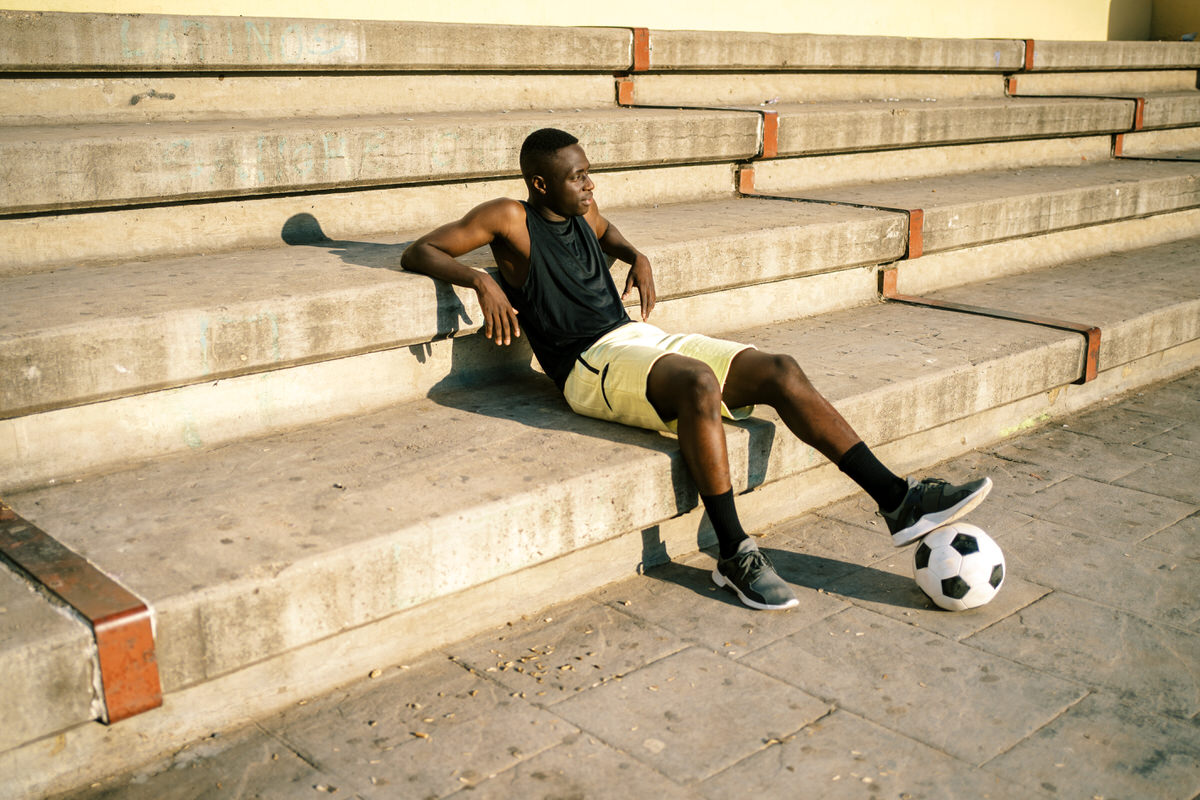 Black football player resting during training